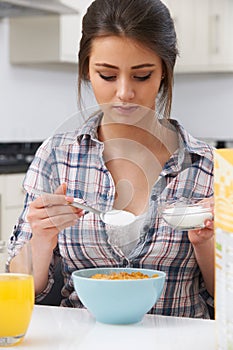Teenage Girl Adding Sugar To Breakfast Cereal