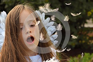 Teenage girl in angel costume blows flying feathers