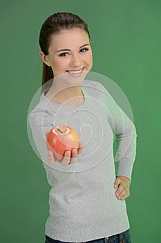 Teenage girl with apple. Happy teenage girl holding an apple while standing isolated on coloured background