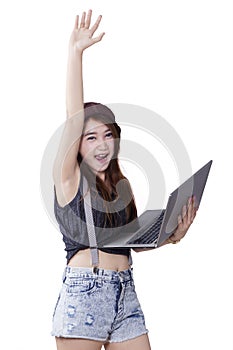 Teenage girl with arms raised using laptop