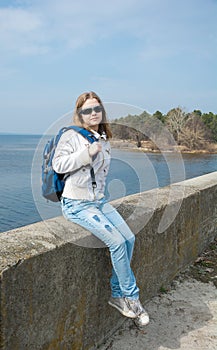 A teenage girl with a backpack in front of the sea