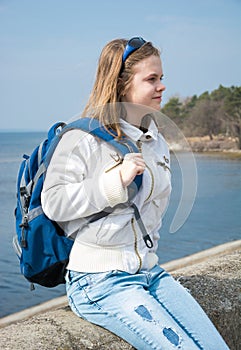 A teenage girl with a backpack in front of the sea