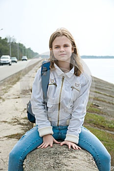 A teenage girl with a backpack in front of the sea
