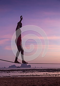 Teenage girl balancing on slackline with sky view on the beach photo