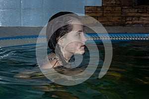 A teenage girl is bathing in a Jacuzzi. A child in a pool with dim lights