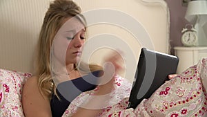 Teenage Girl In Bed Using Tablet Computer Being Bullied