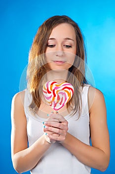 Teenage girl with big lollipop on blue background