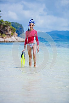 Teenage girl in bikini carrying scubadiving equipment