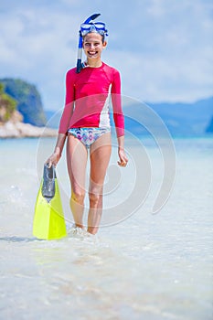 Teenage girl in bikini carrying scubadiving equipment