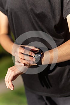 Teenage girl in black clothes checking her fitness watch after a workout