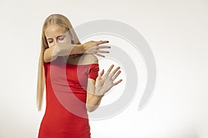 Teenage girl with blond hair and in a red dress sneezes