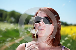 Teenage girl blowing dandelion seed head