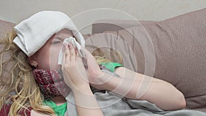 Teenage girl blows her nose in a paper handkerchief. She has a cold