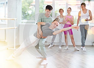 Teenage girl and boy practicing ballet positions in pair in dance studio