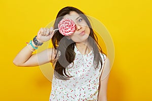 Teenage girl on bright vivid yellow background holding lollipop