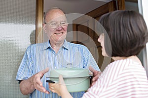 Teenage Girl Bringing Meal For Elderly Male Neighbour photo