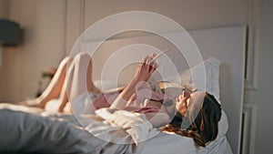 Teenage girl browsing smartphone lying on cozy bed. Relaxed woman texting mobile