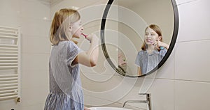 A teenage girl brushes her teeth with an electric toothbrush in the morning