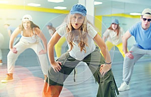 Teenage girl in cap training breakdance Toprock moves in dance hall