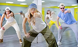 Teenage girl in cap training breakdance Toprock moves in dance hall