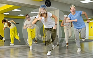 Teenage girl in cap training breakdance Toprock moves in dance hall