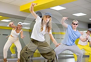 Teenage girl in cap training breakdance Toprock moves in dance hall