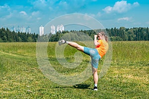 Teenage girl in casual clothes training karate kata outdoors, performs the uro mawashi geri hook kick