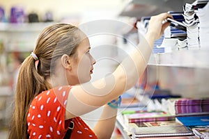Teenage girl is choosing copybook in bookshop