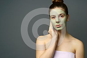 Teenage girl with clay mask on her face and hand photo