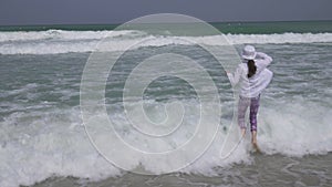 Teenage girl in clothes joyfully jumping in the waves of Persian Gulf on beach of Dubai