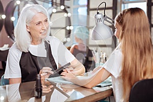 Teenage girl communicating with her manicurist in a nail salon