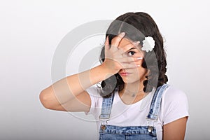 Teenage girl covering eyes and looking thru space between fingers