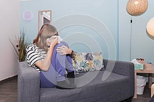 Teenage girl crying on the couch in the therapy room during her session.