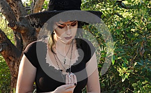 Teenage girl demonstrates her Wiccan belief by wearing black clothes and various charms such as a raven`s skull and a silver moon photo