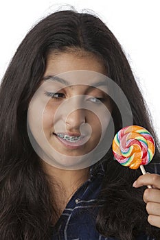 Teenage girl with dental braces looking at a lollypop