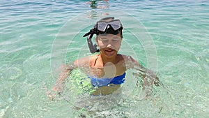 Teenage girl in diving mask standing in shallow water of blue sea