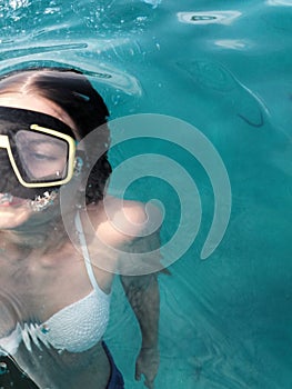 A teenage girl diving with swim mask wearing swimsuit in a clean water of mediteran sea photo