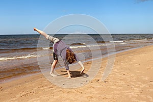 Teenage girl doing a cartwheel on a beach in Latvia