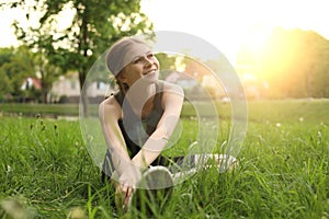 Teenage girl doing morning exercise on green grass in park