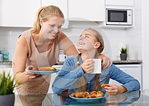 Teenage girl drinking tea with mother