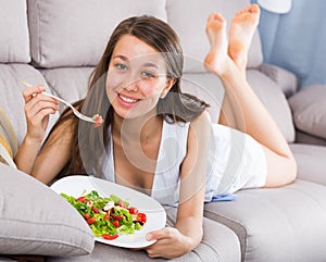 Teenage girl is eating salad because she being on vegetable diet