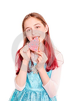 A teenage girl eats gingerbread in the form of a Christmas tree. Girl portrait isolate on white