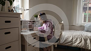 Teenage girl wearing headphones elearning from home using computer app photo