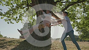 Teenage girl enjoy swinging, boy pushing the rope swing