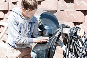 Teenage girl equestrian cleans black Leather Horse Saddle