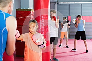 Teenage girl exercising at boxing on punching bag