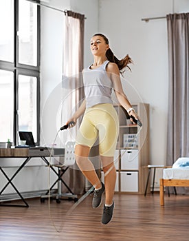 teenage girl exercising with jump rope at home