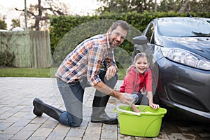 Teenage girl and father washing a car on a sunny day