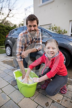 Teenage girl and father washing a car