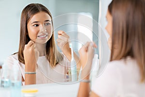 teenage girl with floss cleaning teeth at bathroom